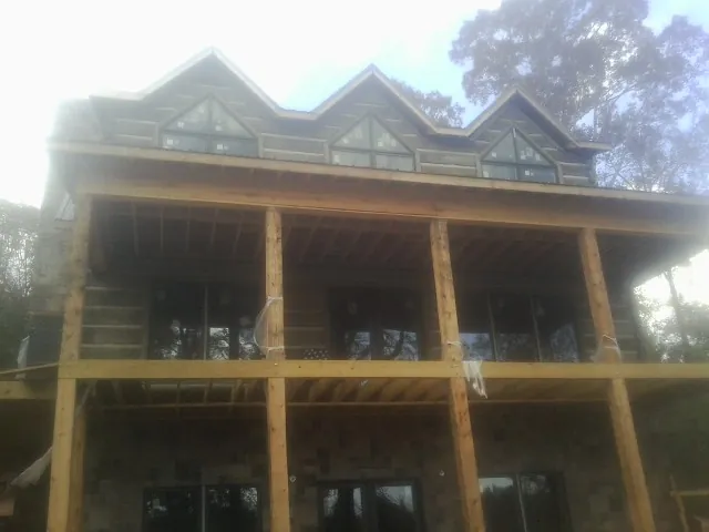 Dormers and porch framing on a large log home under construction — Roof Coating work by our crew in Corbin