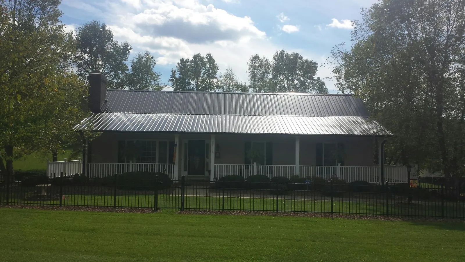 Gray metal roof on a brick ranch with a full width front porch — Gutter Guard Installation work by our crew in Corbin